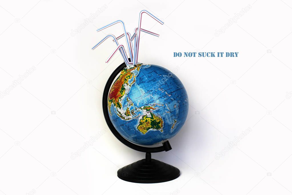 A globe of the earth with cocktail plastic straws in it over white background, ecological problem concept, save water, do not suck the earth dry. Message for social advertising, place for inscription