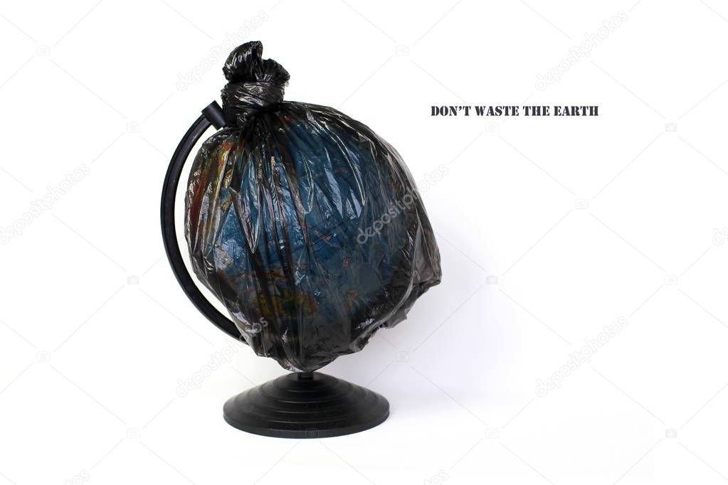 A globe of the earth in a plastic black bag like trash over white background, the concept of ecology problem and World Environment Day. Photo with message for social advertising, place for inscription