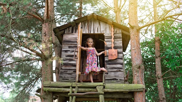 Счастливый милый ребенок играет в домике на дереве — стоковое фото