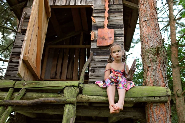 Yazın ağaç evde tek başına oturan sevimli çocuk