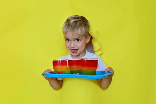 Niño sosteniendo un plato con gelatina de colores a través de un agujero de papel — Foto de Stock