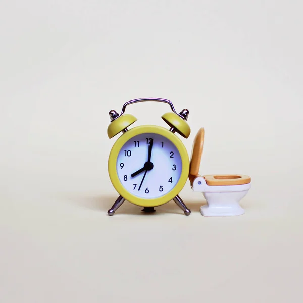 Yellow alarm clock and white toilette bowl — Stock Photo, Image