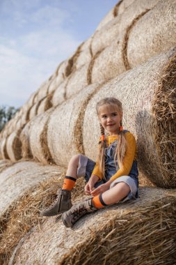 Tarlada saman balyalarında eğlenen tatlı kız.