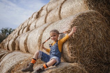 Tarlada saman balyalarında eğlenen tatlı kız.