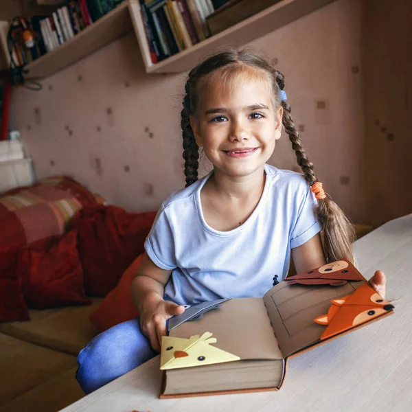 Девушка держит книгу с искусной бумажной закладкой — стоковое фото