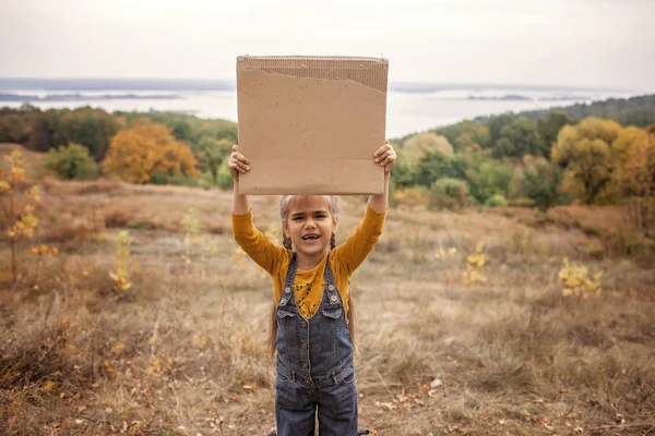 Niños pequeños sosteniendo un cartel sobre el fondo de la naturaleza de otoño — Foto de Stock