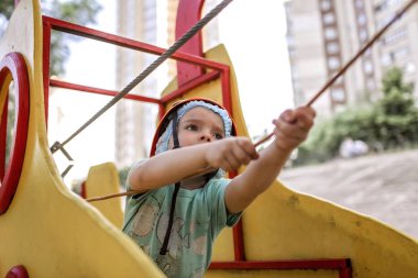 Çocuk macera parkında ip yapısında eğleniyor.