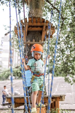 Çocuk macera parkında ip yapısında eğleniyor.