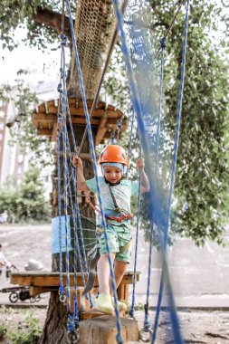 Çocuk macera parkında ip yapısında eğleniyor.