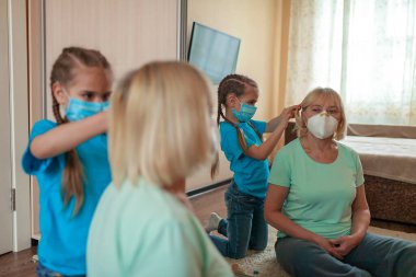 Çok nesilli ilişkiler, yeni normal hayattaki yaşlılarla ilgilenmek, büyükannesiyle eğlenen tatlı bir kız medikal solunum cihazları takmak ve evde birlikte saç yapmak, sosyal mesafe kuralı.
