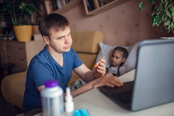 Middle-aged father looking at laptop screen and consulting with a doctor online at home, telehealth services during lockdown, distant video call, modern tech healthcare application