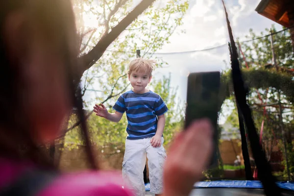 Jonge Jongen Springt Trampoline Zonnige Zomerdag Haar Zus Filmt Dit — Stockfoto