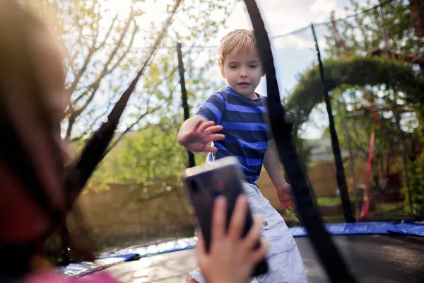 Jonge Jongen Springt Trampoline Zonnige Zomerdag Haar Zus Filmt Dit — Stockfoto