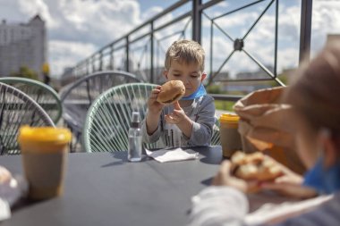 Yeni normal gerçeklik, sokak kafesinde güvende olmak, tıbbi maskeli baba fast food restoranında öğle yemeği, açık hava aile yemekleri.