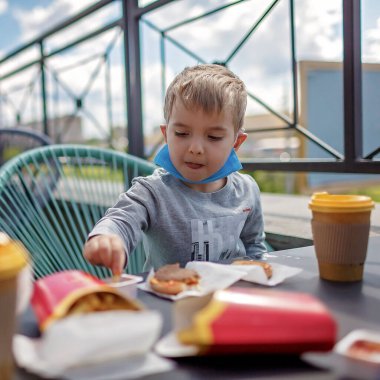 Yeni normal gerçeklik, sokak kafesinde güvende olmak, tıbbi maskeli baba fast food restoranında öğle yemeği, açık hava aile yemekleri.