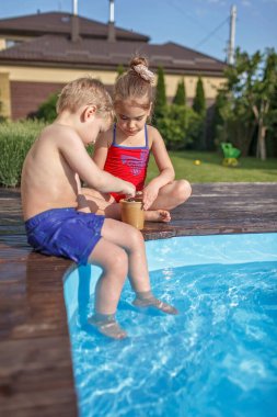 Yazlık evde aile hafta sonu, yerel tatil. Tatlı çocuklar, erkek ve kız, yüzme havuzunun yanında çikolatalı dondurma yiyip eğleniyorlar, mutlu yaz zamanları, açık hava yaşam tarzı.