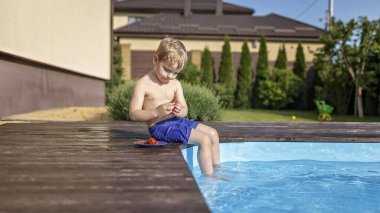 Yazlık evde aile hafta sonu, yerel tatil. Tatlı çocuklar yüzme havuzunun yanında eğlenceli ve sulu çilekler yiyorlar. Mutlu yaz tatilleri, açık hava yaşam tarzları.