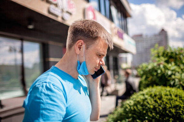 Новая нормальная реальность, оставаться в безопасности в уличном кафе, человек в защитной медицинской маске, держа бумажные стаканчики и разговаривая на смартфоне, открытая семейная еда
