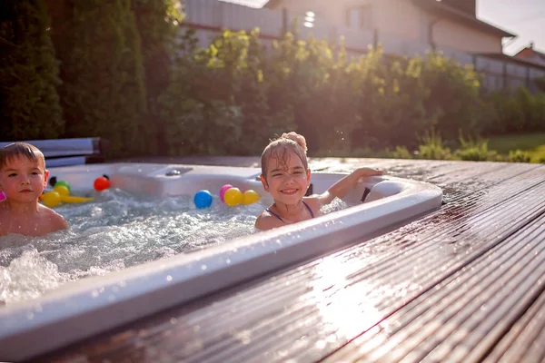 Family weekend in summer cottage, local staycation. Cute kid having rest in bathtub with bubby water one hot day, happy summertime, outdoor lifestyle