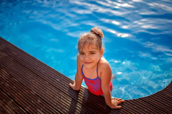 Family weekend in summer cottage, local staycation. Cute kid have a fun and cooling off in the swimming pool one hot day, happy summertime, outdoor lifestyle