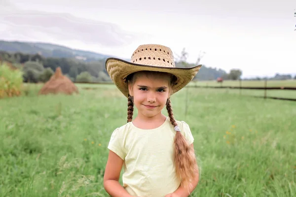 Local vacation, stay safe, stay home. Little girl in cowboy hat playing in western in the farm among mountains, happy summertime in the countryside, childhood and dreams