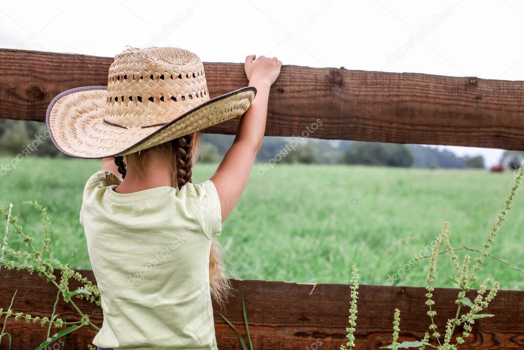 Local vacation, stay safe, stay home. Little girl in cowboy hat playing in western in the farm among mountains, happy summertime in the countryside, childhood and dreams