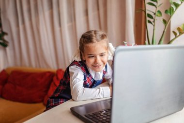 Okula dönmek, yeni normal eğitim. Okul üniformalı tatlı bir kız video görüşmesiyle birini selamlıyor ve yeni sırt çantasını gösteriyor. Sosyal uzaklık öğrenimi ve yeni rehberlik