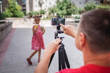İnternetten para kazan. Aile kanalı, video blogcusu, internet kazancı ve uzaktan kumandalı serbest çalışma için kızıyla birlikte orta yaşlı bir baba film kaydediyor.