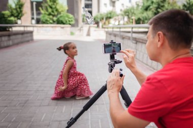 İnternetten para kazan. Aile kanalı, video blogcusu, internet kazancı ve uzaktan kumandalı serbest çalışma için kızıyla birlikte orta yaşlı bir baba film kaydediyor.
