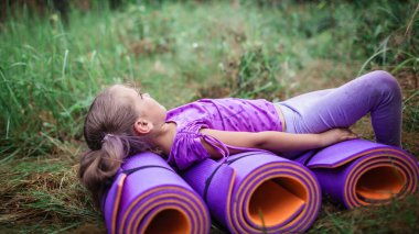 Aktif sağlıklı bir hafta sonu. Mutlu çocuk ormanda yürüyüş yaparken mor yoga minderinde dinleniyor ve eğleniyor. Yeni normal hayatımızda kalmak. Yazın açık hava yaşam tarzı