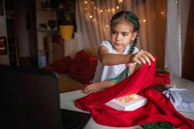 Zero waste Christmas wrapping. Cute girl learning to wrap gifts in traditional Japanese style furoshiki via internet, online educational video. Sustainable celebration clipart