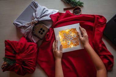 Noel ambalajı sıfır. Sevimli kız geleneksel Japon tarzı furoshiki 'yi internet üzerinden, online eğitim videosuyla paketlemeyi öğreniyor. Sürdürülebilir kutlama