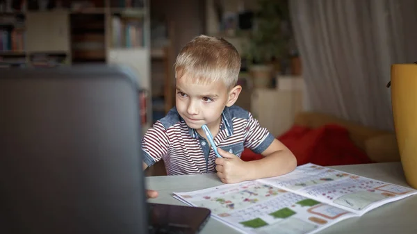 Distant education, online class meeting. 5-6 years school boy studying homework during his online lesson at home, social distance during quarantine, self-isolation, communication via internet