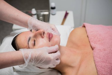 Güzellik uzmanı güzellik salonundaki kadın müşteriye yüz bakımı yapıyor.. 