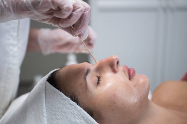 Güzellik uzmanı, güzellik salonunda pamuklu çubukla kadın yüzüne kozmetik tedavi uyguluyor.. 