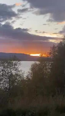 Sonbahar ağaçları ve Laponya Finlandiya 'da dramatik bulutlu gökyüzü ile birlikte dağ gölünün üzerinde gün batımı. 