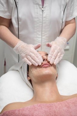 Güzellik uzmanı güzellik salonundaki kadın müşteriye yüz bakımı yapıyor.. 