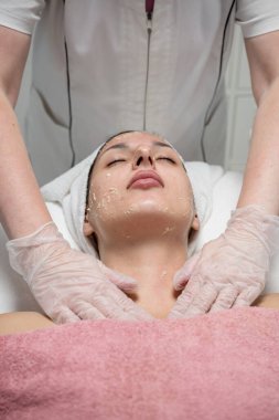 Güzellik uzmanı güzellik salonundaki kadın müşteriye yüz bakımı yapıyor.. 