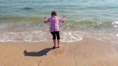 Deniz kenarında bir dalga ile oynayan kız