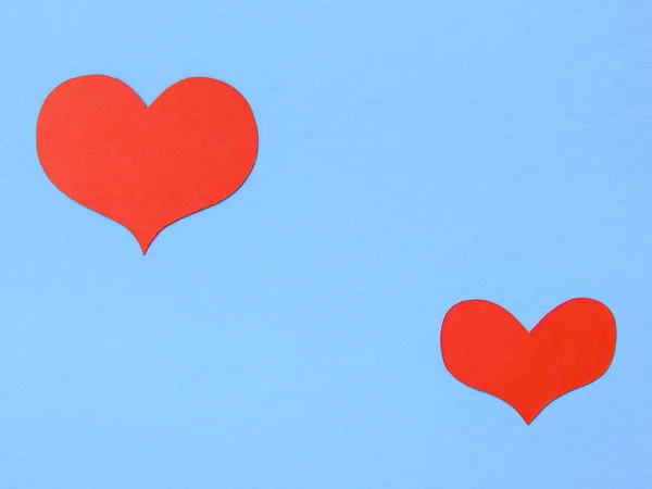 Red paper hearts on a blue paper background
