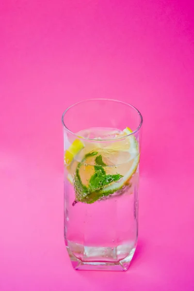 Su, limon ve nane pembe bir arka plan üzerinde.
