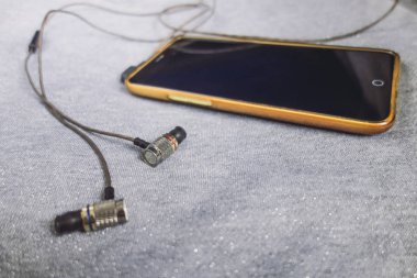 Parlak gümüş arka plan üzerinde kulaklık ile sarı telefon.