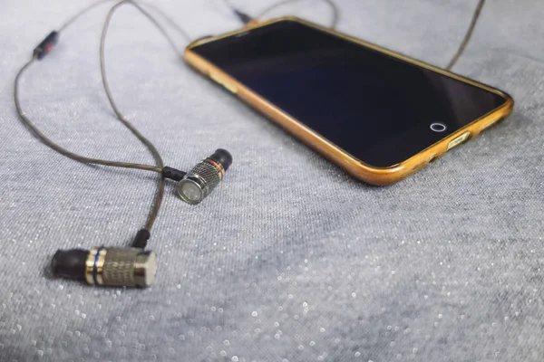 Parlak gümüş arka plan üzerinde kulaklık ile sarı telefon.