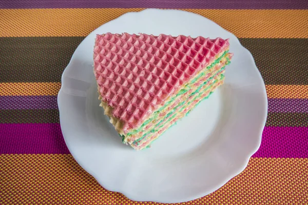 Multicolored waffle cake with condensed milk on a white plate. — Stock Photo, Image