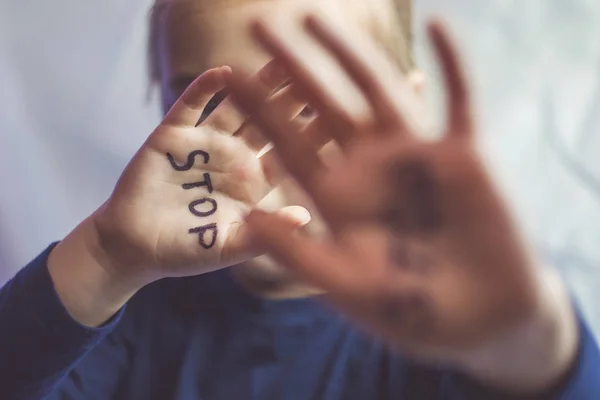 Aile içi şiddet ve çocuk abusement kavramı. Küçük bir kız elini kelime üzerinde yazılı Stop ile gösterir. Çocuklar şiddet.