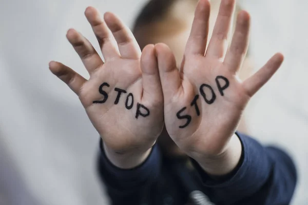 Concepto de violencia doméstica y abuso infantil. Una niña muestra su mano con la palabra DETENER escrita en ella. Violencia infantil . —  Fotos de Stock