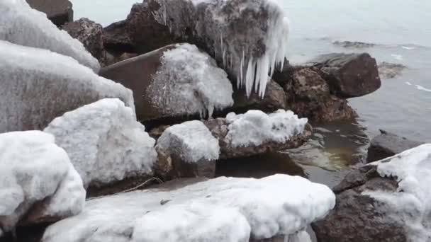 Pietre sul mare coperte di ghiaccio e con ghiaccioli appesi ad esse . — Video Stock