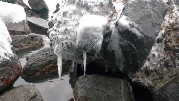 Pietre sul mare coperte di ghiaccio e con ghiaccioli appesi ad esse . — Video Stock