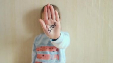 Aile içi şiddet ve çocuk abusement kavramı. Küçük bir kız elini kelime üzerinde yazılı Stop ile gösterir. Çocuklar şiddet.