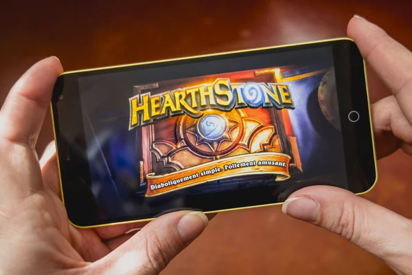 Berdyansk, Ukraine - 4 mars 2019 : Mains tenant un smartphone avec intro Hearthstone à l'écran . — Photo